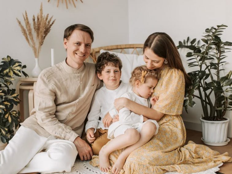 Happy family of four enjoying quality time together in a cozy, plant-filled room.